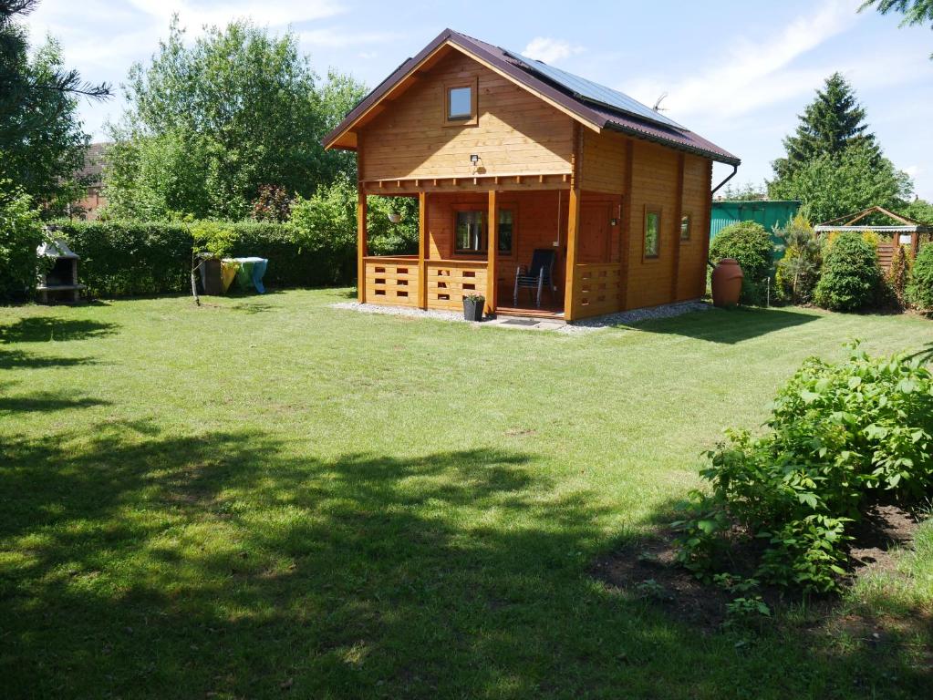 a small wooden cabin in a yard with a grass field at Domek letniskowy drewniany nad Jeziorem Strzeszowskim nowy in Strzeszów