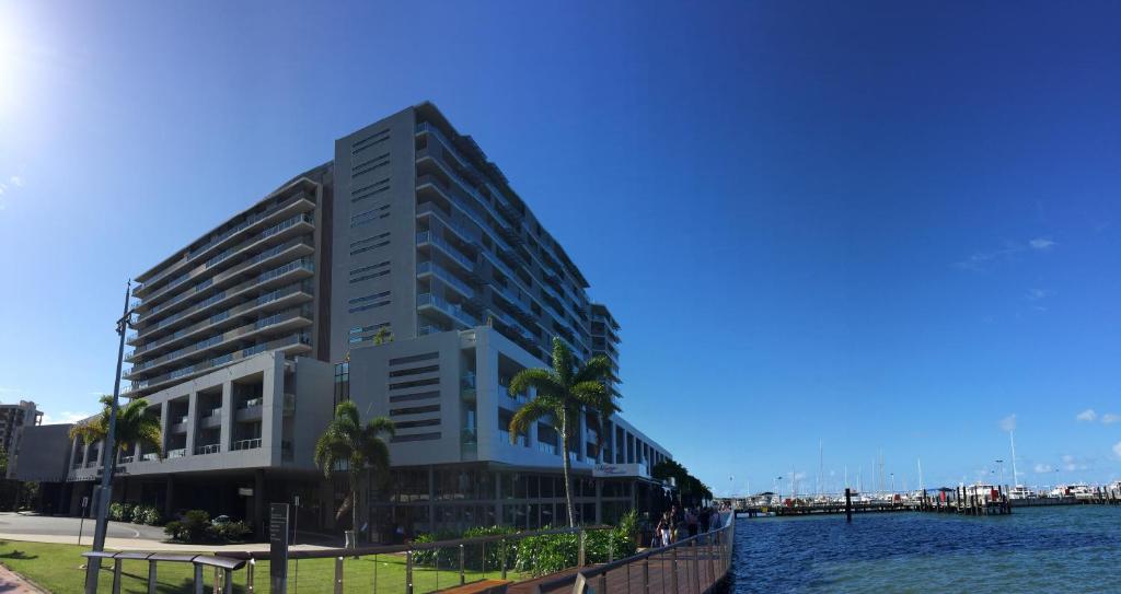 wysoki budynek z palmami przed wodą w obiekcie Cairns Private Apartments w mieście Cairns