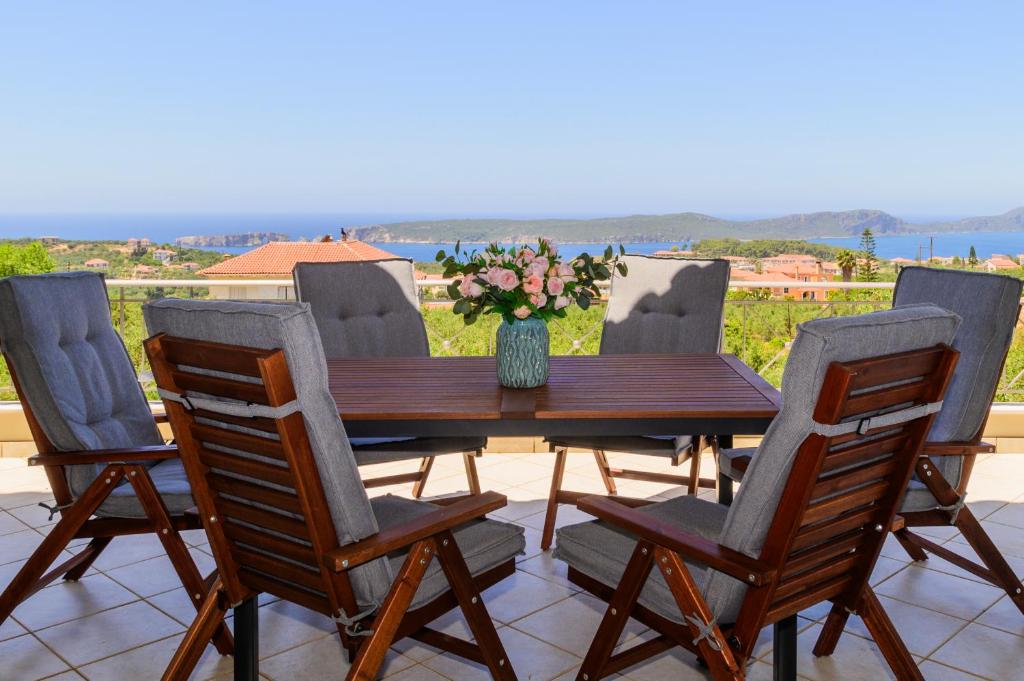 a wooden table with four chairs and a vase with flowers at Villa Katrin 2 in Pylos