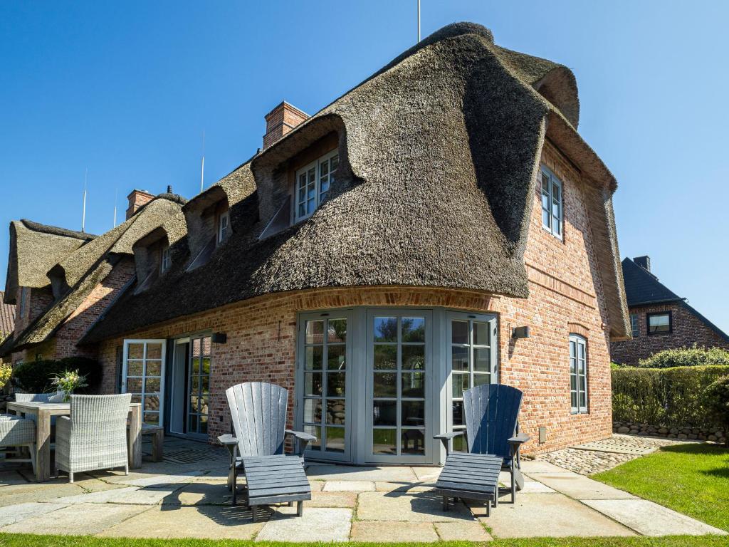 Casa con techo de paja, sillas y patio. en Haus Riva, en Wenningstedt