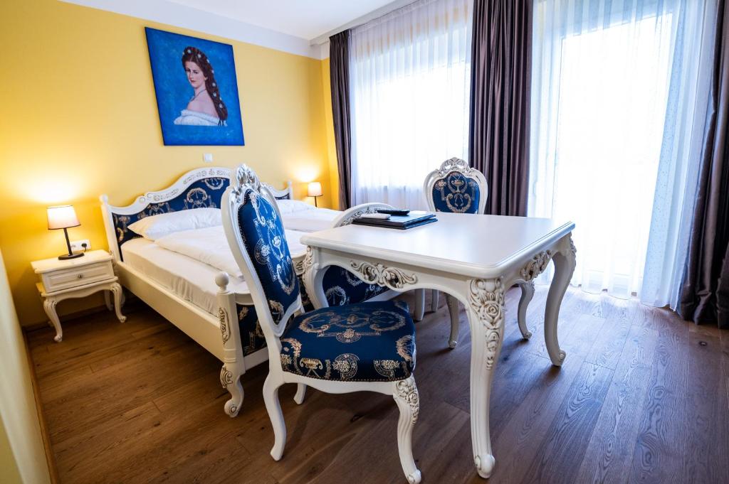 a bedroom with a bed and a table and chairs at Hotel Vulkan Residenz - Self-Check-in in Leibnitz