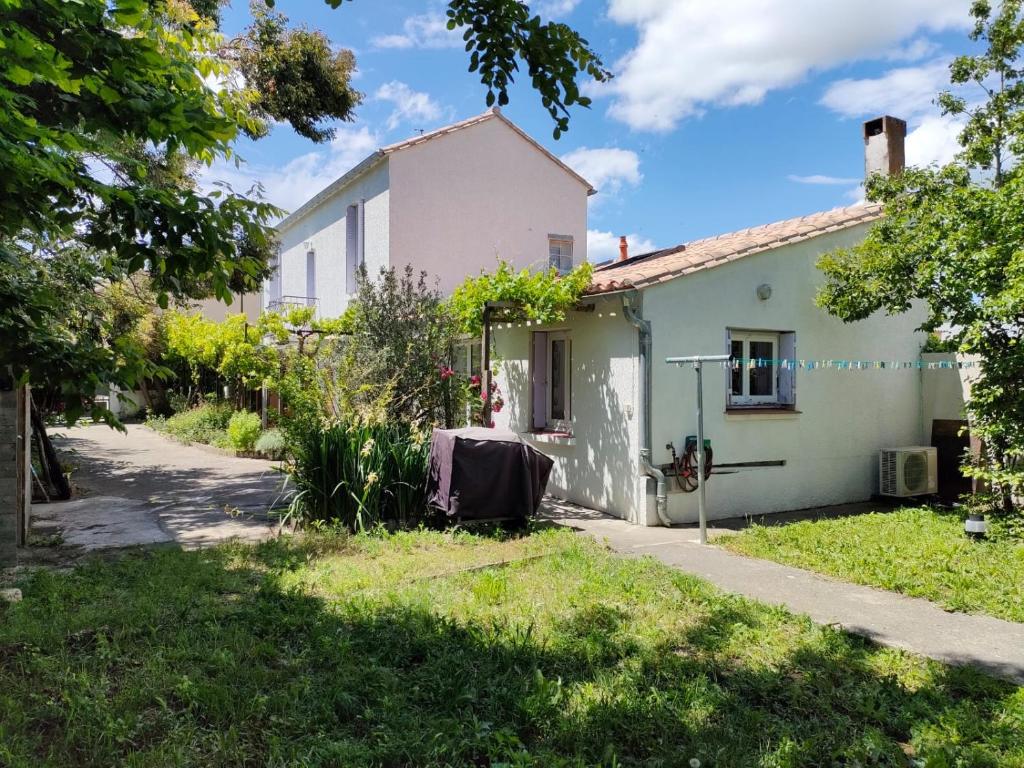 une maison blanche avec une cour devant elle dans l'établissement Maison Bocage - lumineuse avec jardin, à Carcassonne