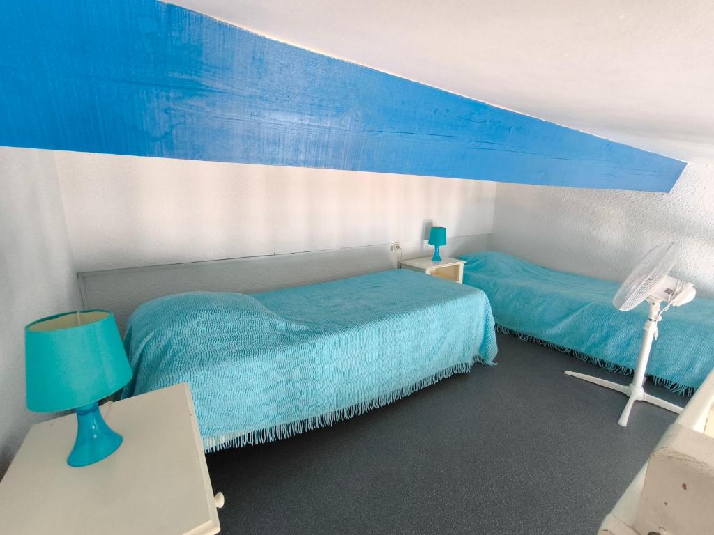 a bedroom with two beds and a blue canopy at Appartement Port Barcarès Vue Marina in Le Barcarès