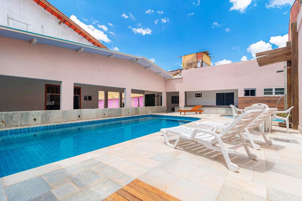 - une piscine avec 2 chaises blanches à côté d'une maison dans l'établissement Pousada Meia Lua, à Pirenópolis