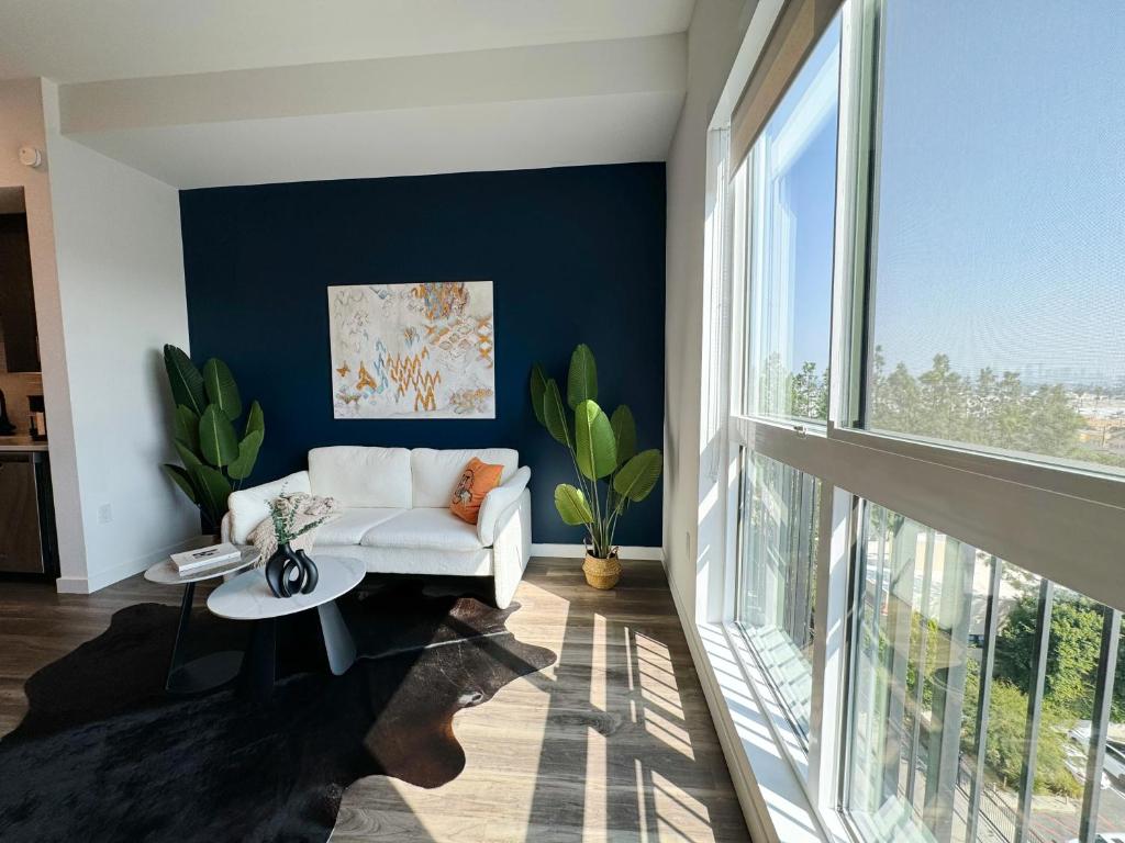 a living room with a white couch and a large window at Cosmopolitan Hollywood Home DTLA view Parking - 10mins to Universal Studios in Los Angeles