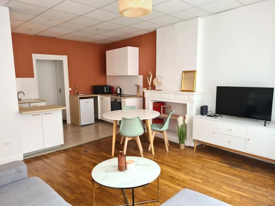 a living room with a table and chairs and a kitchen at Joli appartement en centre-ville in Chalon-sur-Saône