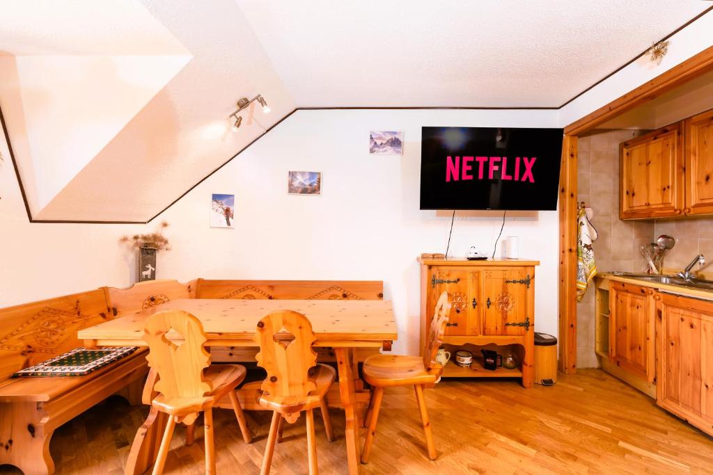 una cucina con tavolo, sedie e TV di Mara's House - Piste da Sci e Garage privato a Sauze d'Oulx