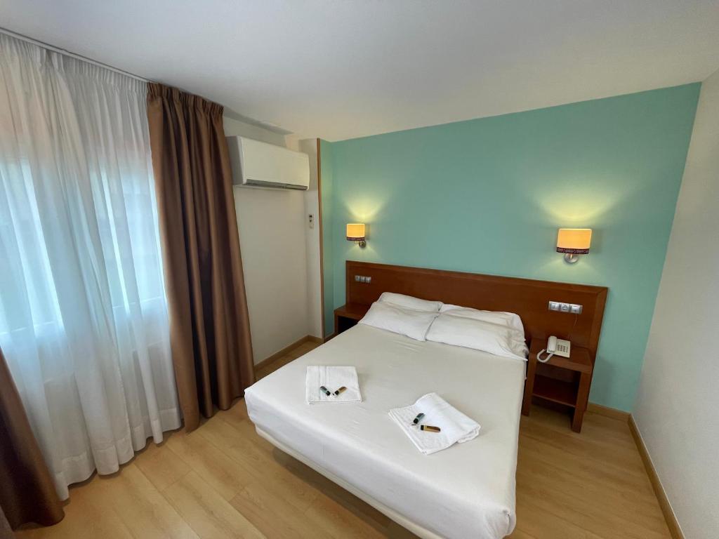 Hotel Spa Playa Langosteira by Adeloló في فينيستيري: غرفة نوم عليها سرير وفوط
