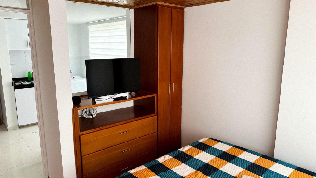 a bedroom with a television in a wooden cabinet at aparta estudio INTELIGENTE Tunja al lado de la UPTC in Tunja