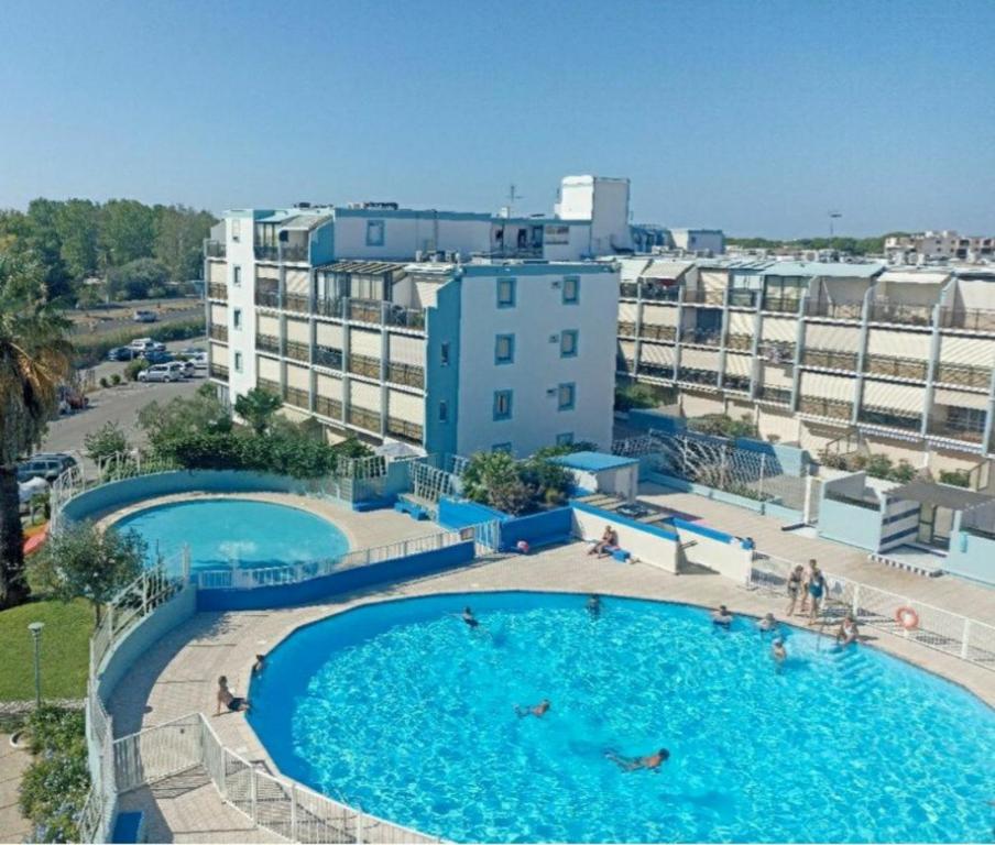 une vue aérienne de deux piscines avec des bâtiments en arrière-plan dans l'établissement Double studio cabine Grau du Roi, au Grau-du-Roi