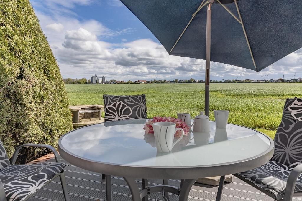 a white table and chairs with an umbrella at 50099Deichnest in Carolinensiel