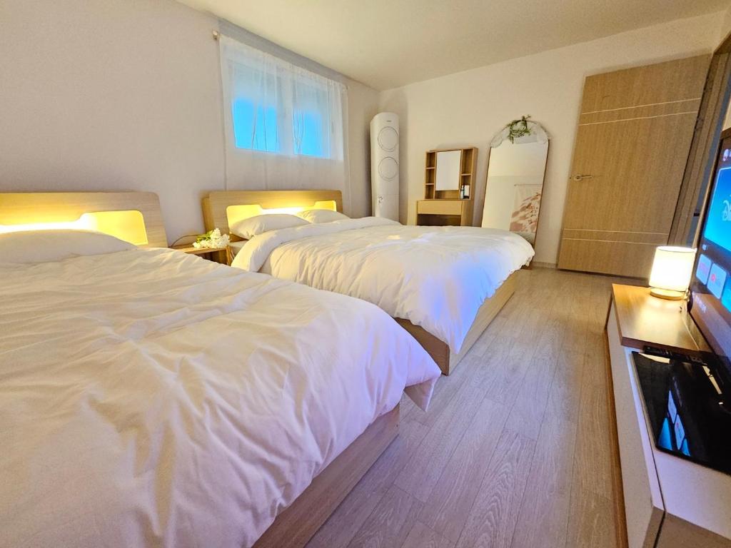 a hotel room with two beds and a flat screen tv at H Stay in Incheon