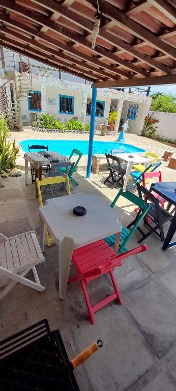 eine Gruppe von Tischen und Stühlen vor einem Pool in der Unterkunft AP03-A 50 Metros da Praia Flats Mobiliados para 4 pessoas in Paulista