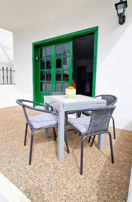 a white table with two chairs and a green door at Apartamento de la Playa II in Tías