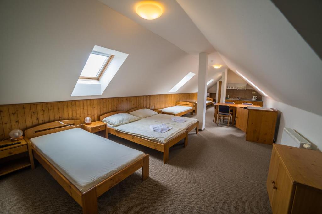 a attic room with two beds and a staircase at Hotel Elsyn Dvůr in Stachy