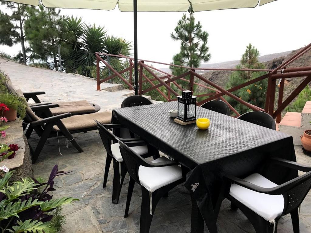 una mesa negra con sillas y una sombrilla en el patio en Finca Las Polinarias Casa Cueva en Fasnia en Santa Cruz de Tenerife