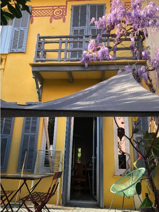 un bâtiment jaune avec une table, des chaises et un parasol dans l'établissement Villa Nice, à Nice
