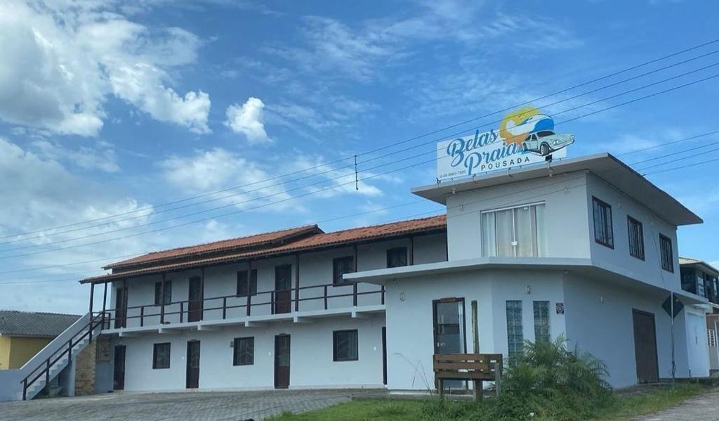 a white building with a sign on top of it at Pousada Belas Praia quarto Praia do Porto in Imbituba