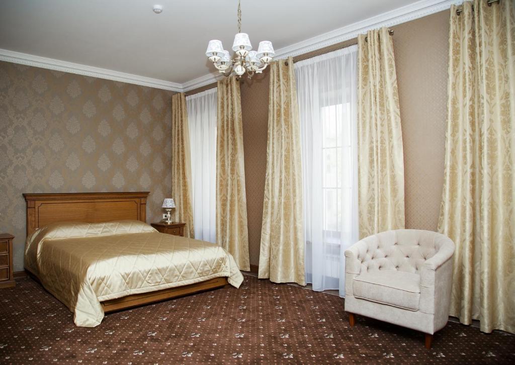 um quarto com uma cama, uma cadeira e um lustre em Rossiya Hotel em Vol'sk