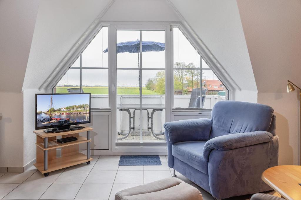 sala de estar con silla y TV en 50030 Ferienwohnung Nordwind en Carolinensiel