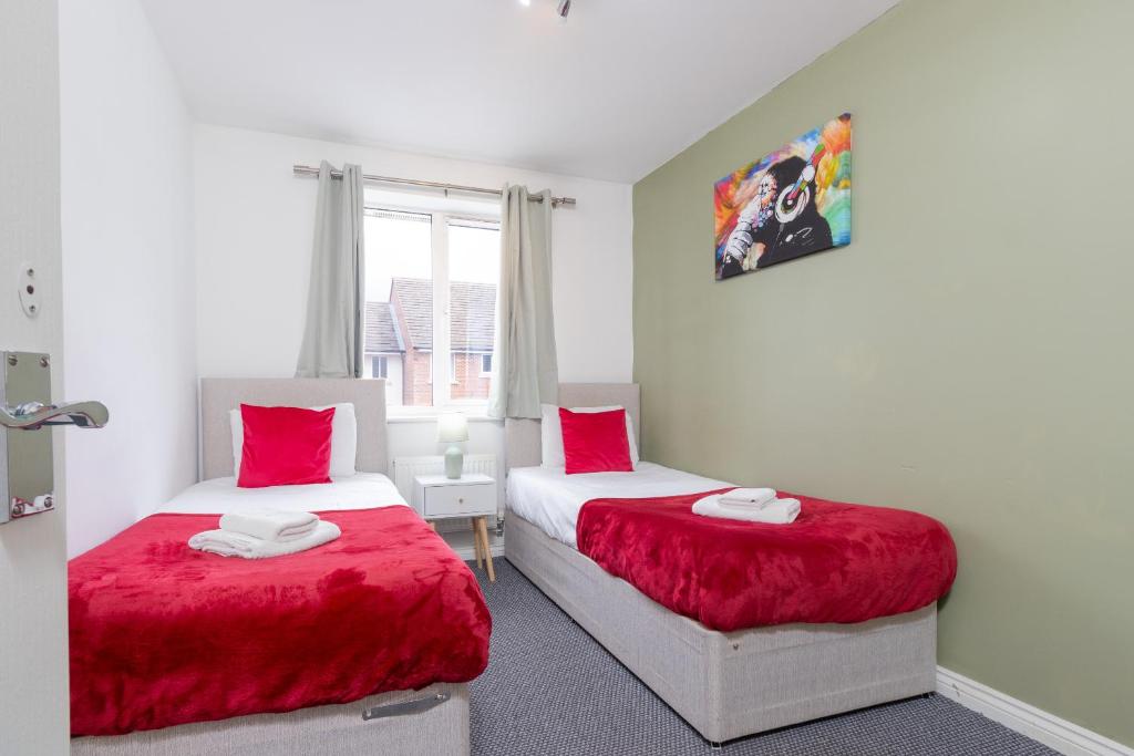 two beds in a room with red pillows at 2-BR Executive En-Suite Apartment by MBiZ in Coventry