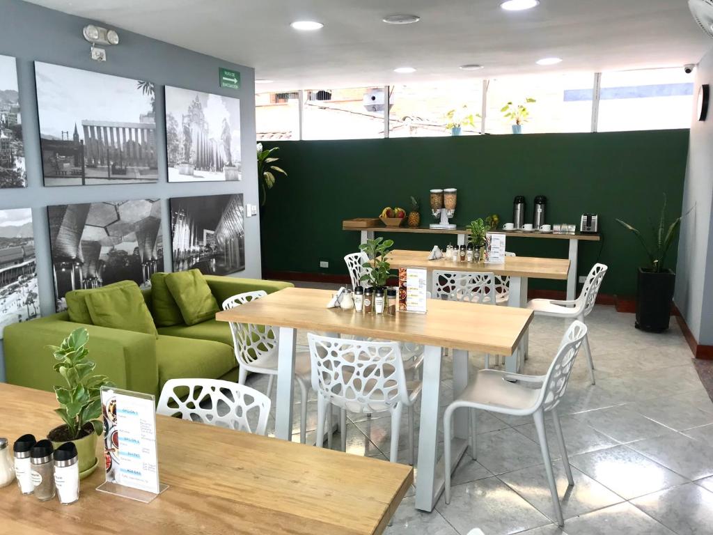 a restaurant with tables and chairs and a green couch at Poblado Park Guest House in Medellín