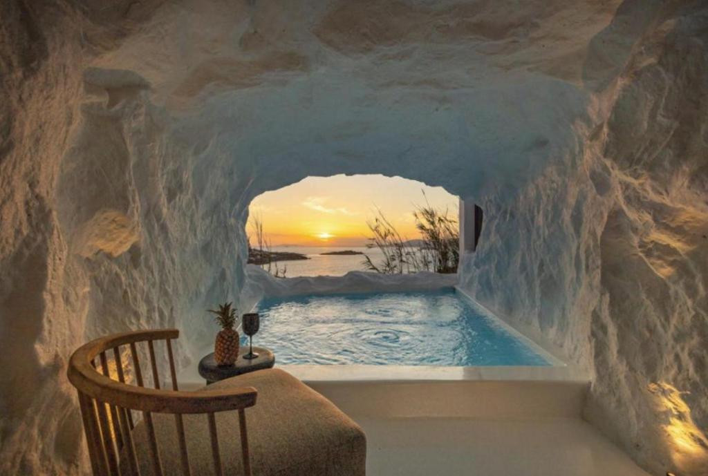 une chambre avec vue sur une piscine dans un mur de pierre dans l'établissement Exquisite Mykonos Villa Villa Apocryphos 6 Bedrooms Unique Aegean Sea View, à Glastros