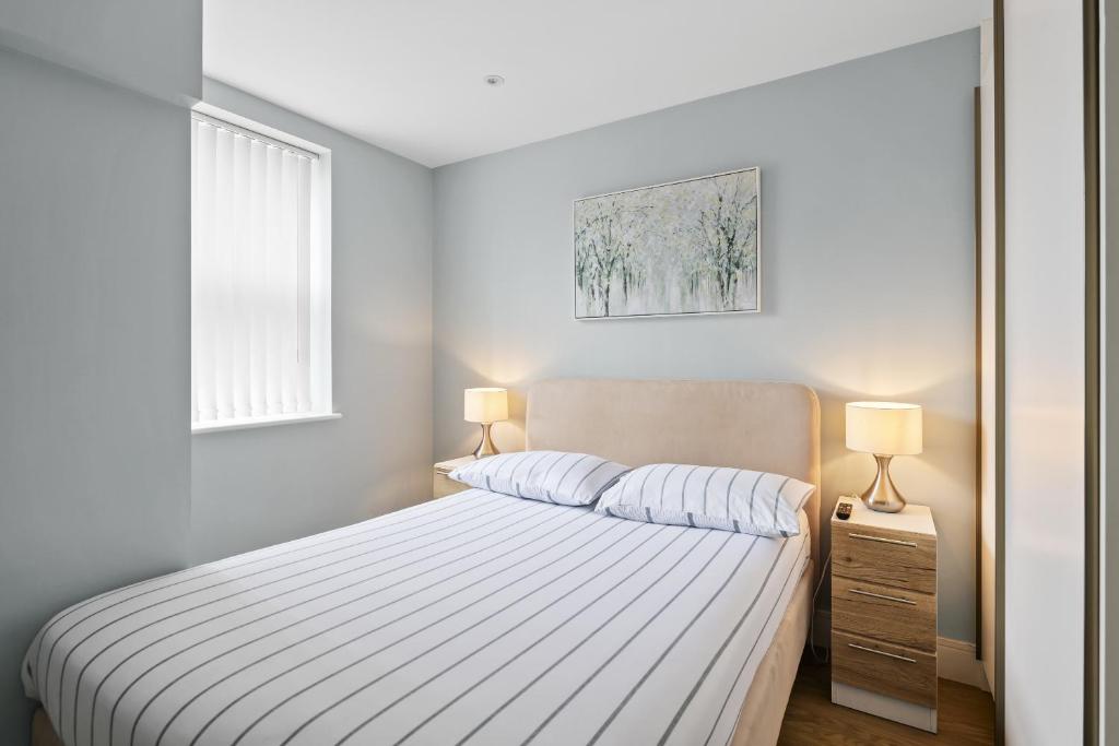 a white bedroom with a bed and a window at Luxurious One Bedroom Apartment in Bond Street in Chelmsford