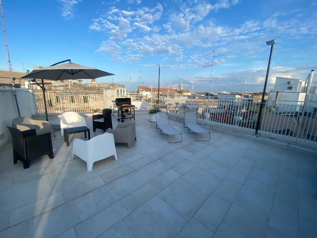 einen Balkon mit Stühlen, Tischen und einem Sonnenschirm in der Unterkunft Casa Bianca bnb Big Terrace 10min Airport, Beach in Bitonto