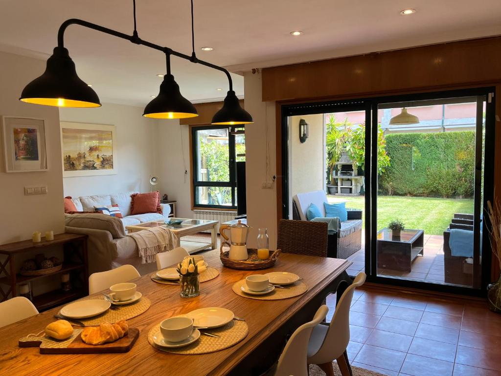 Un comedor y una sala de estar con mesa y sillas. en Exclusiva casa en playa América, cerca de Baiona, en Nigrán