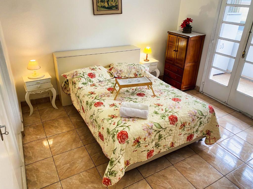 een kleine slaapkamer met een bed met een bloemenbed bij Apartamento Teresópolis - Centro in Teresópolis
