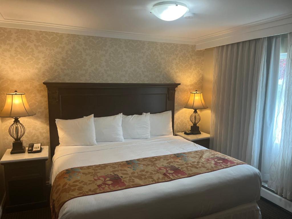 a hotel room with a bed and two lamps at Arbutus Inn in Victoria