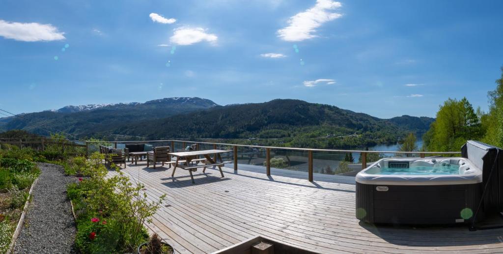 a deck with a hot tub and a picnic table at Fjellhagen in Bjørkheim