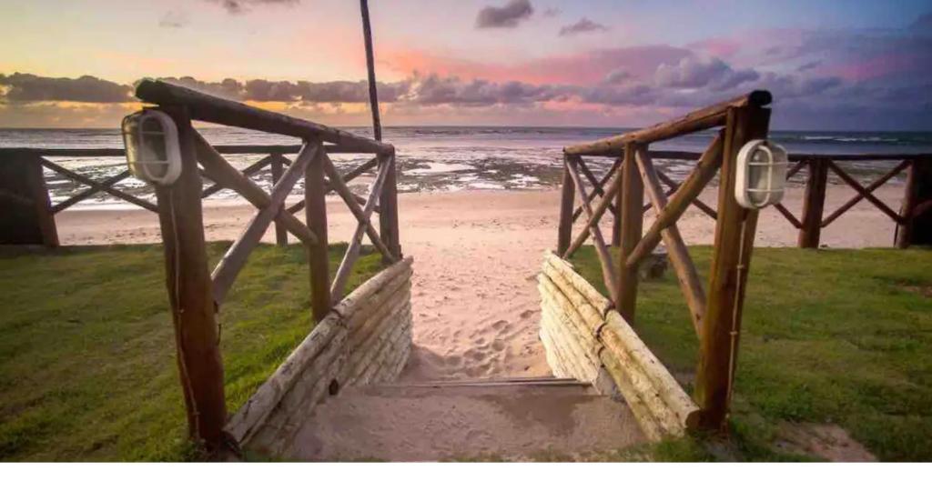 a staircase leading to a beach with the ocean at Casa inteira, pé na areia, conforto, frente mar, Itacimirim, Bahia in Camacari
