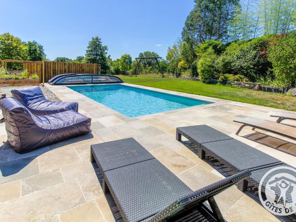 a swimming pool with two lounges and two chairs next to at Roulotte climatisée avec piscine et jardin - FR-1-622-54 in Vihiers