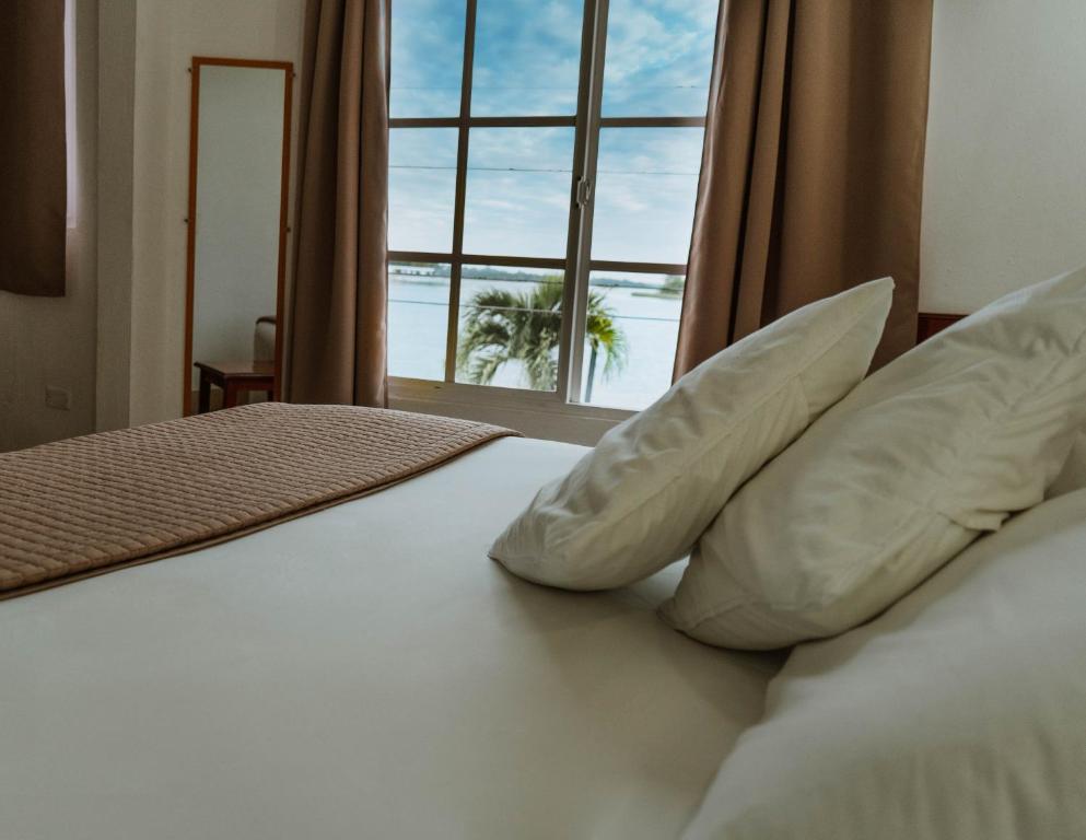 a bed with pillows and a window with a palm tree at Hotel Casa Amelia in Flores