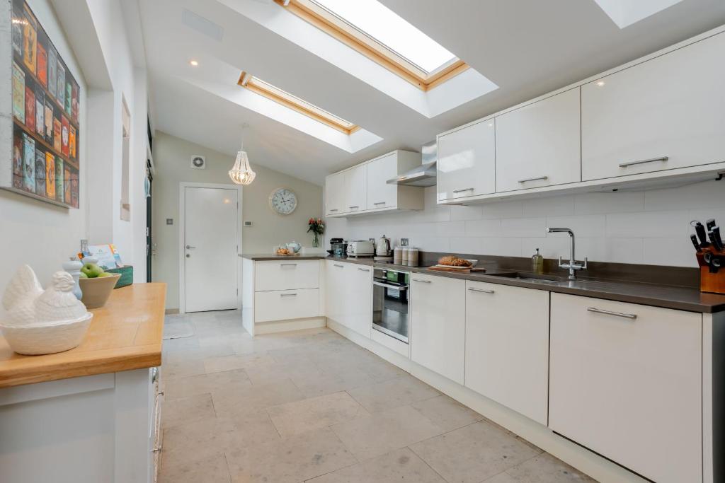 a kitchen with white cabinets and a skylight at Seacombe in Swanage