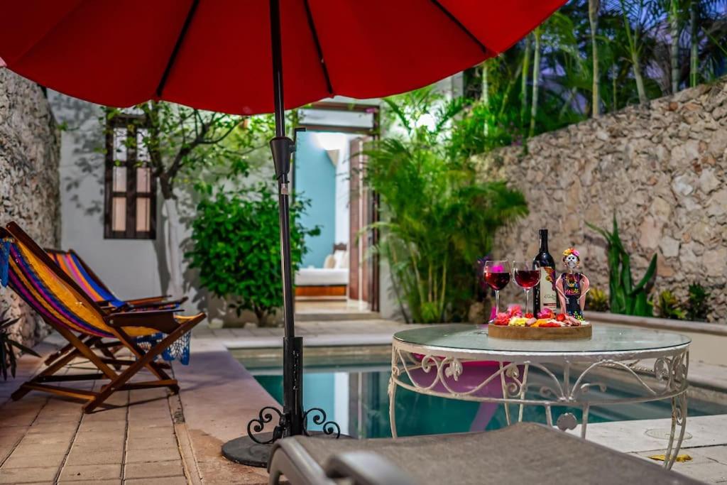 a table with a red umbrella and two glasses of wine at Casa Armadillo, colonial house with pool in Mérida