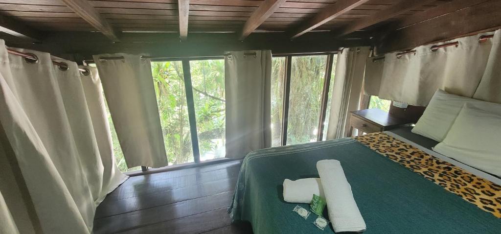 ein Schlafzimmer mit einem Bett in einem Zimmer mit Fenstern in der Unterkunft Chales Internacional in Paraty