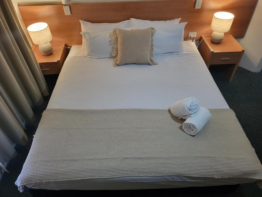 Bundaberg International Motor Inn في بوندابرج: غرفة نوم بسرير كبير عليها منشفتين