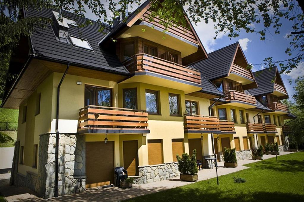 a large yellow house with a black roof at udanypobyt Apartamenty Kominkowe in Zakopane