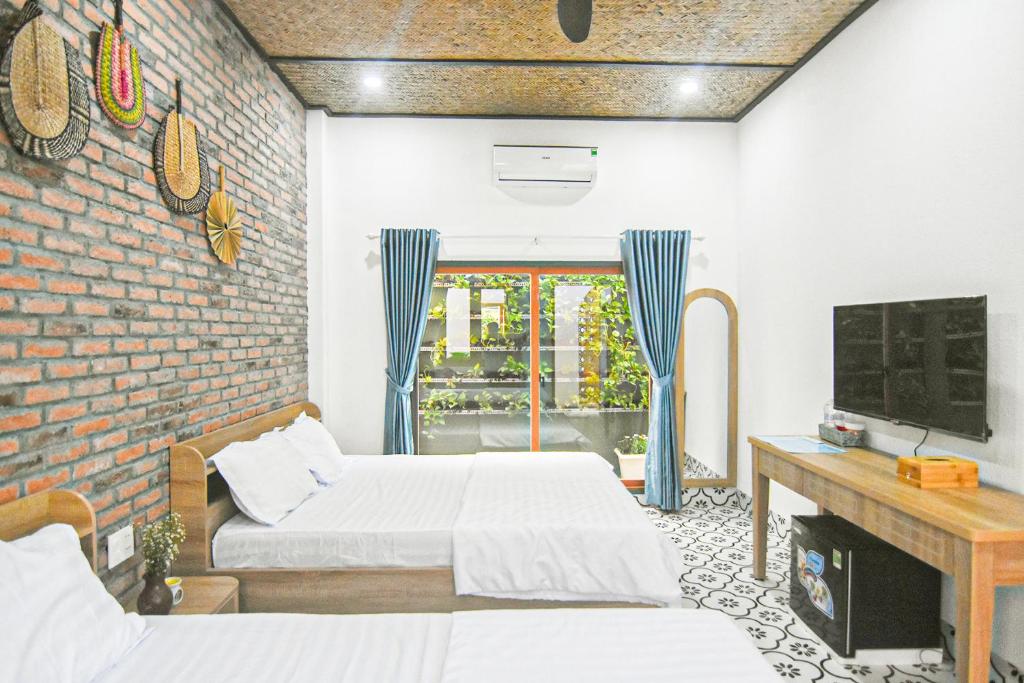 ein Schlafzimmer mit zwei Betten und einer Ziegelwand in der Unterkunft Homestay Phú Mỹ in Phan Thiet