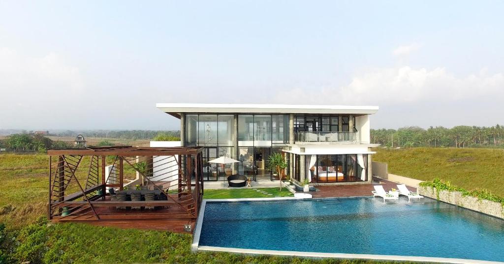 a house with a pool in front of it at Abian Kapas Beach House in Tabanan
