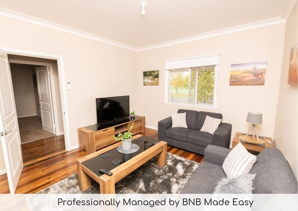 a living room with a couch and a tv at Kinross on Cox Sweet, Neat & Simple + Wifi in Orange