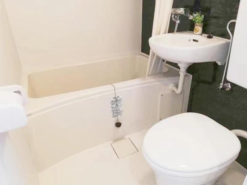 a white bathroom with a toilet and a sink at Shibuya Hana House in Tokyo