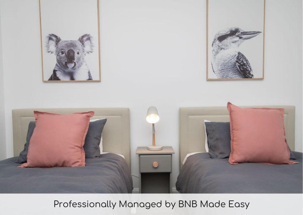 two beds in a bedroom with two pictures of a koala at Villa 88 - Stylish, Modern, Fresh & Light in Orange