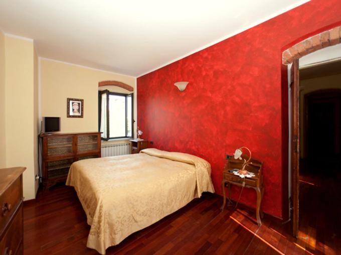 1 dormitorio rojo con 1 cama y pared roja en Vecchia Locanda, en Sarzana