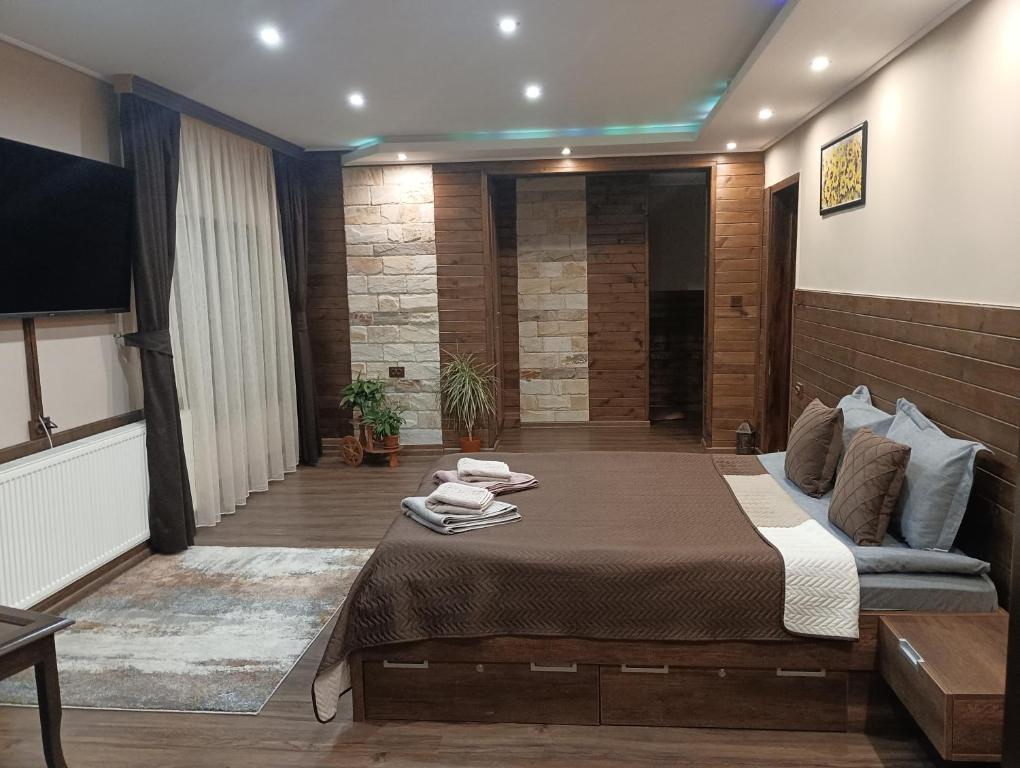 a bedroom with a large bed and a flat screen tv at КръчмЪ при Байката Alpin in Ribarica