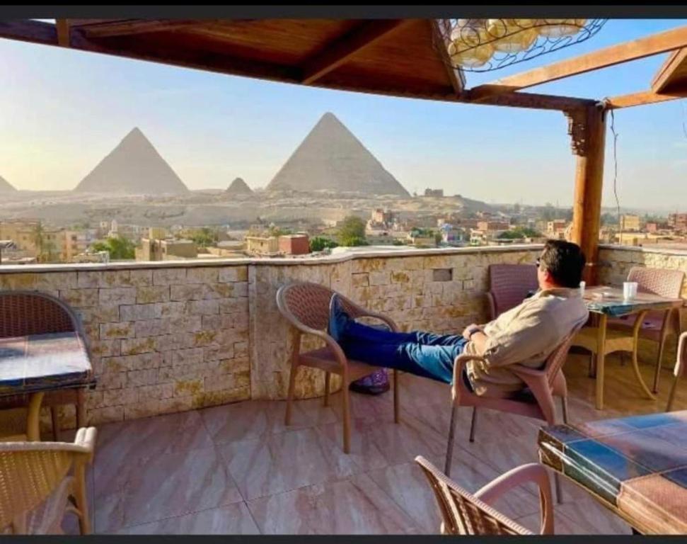 een man die op een balkon zit en naar de piramides kijkt bij City pyramids inn in Caïro