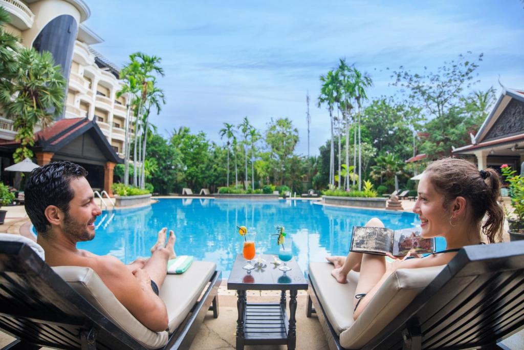 a man and a woman sitting in chairs by a pool at Borei Angkor Resort & Spa in Siem Reap